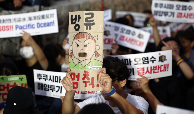 Participants in a candlelight rally on Aug. 24 outside the Japanese Embassy in Seoul protesting Japan’s release of radioactively contaminated water from the Fukushima nuclear plant into the ocean hold up signs including one reading “Stop the release!” (Yonhap)