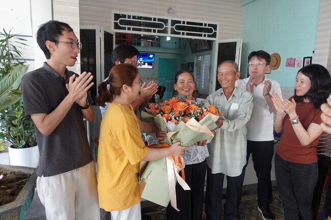 Nguyễn Thị Thanh, a survivor of Korea’s massacres in Vietnam, and witness of the massacre Nguyên Đức Choi smiles as Koreans with the Korea-Vietnam Peace Foundation deliver congratulatory flowers for Thanh’s court win on Feb. 12. (Shin Da-eun/The Hankyoreh)
