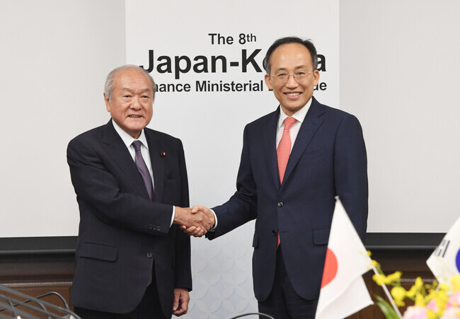 South Korean Finance Minister Choo Kyung-ho (right) shakes hands with his Japanese counterpart, Finance Minister Shunichi Suzuki, at a meeting in Tokyo on June 29. (courtesy of the Ministry of Economy and Finance)