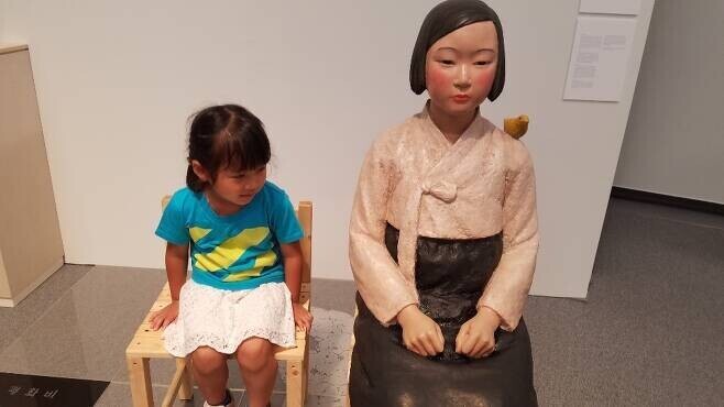 A child sits next to a comfort woman statue at an exhibition at the Aichi Prefectural Museum of Art in 2019. (Cho Ki-weon/The Hankyoreh)