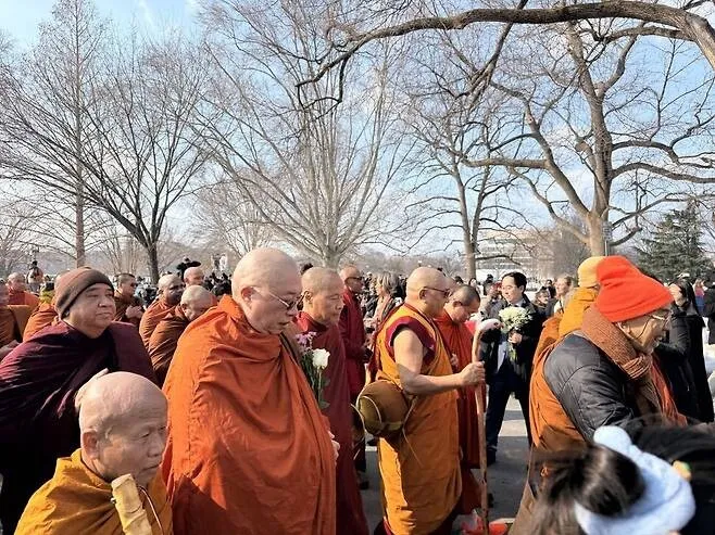 Sen. Andy Kim (D-NJ) handed out flowers to passing monks participating in the “Walk for Peace” as it passed in front of Congress. (Kim Won-chul/Hankyoreh)