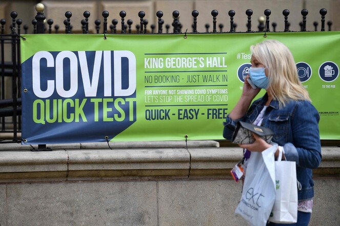 16일 영국 블랙번에서 마스크를 쓴 시민이 코로나19 테스트를 알리는 광고판 앞을 지나고 있다. 블랙번/AFP 연합뉴스