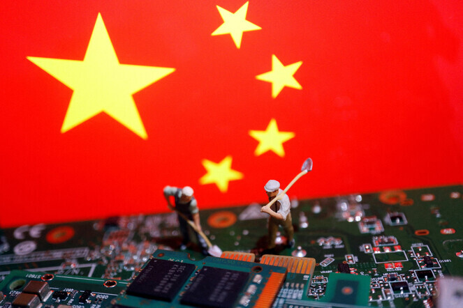 Toy workers on a printed circuit board against the flag of China. (Reuters/Yonhap)