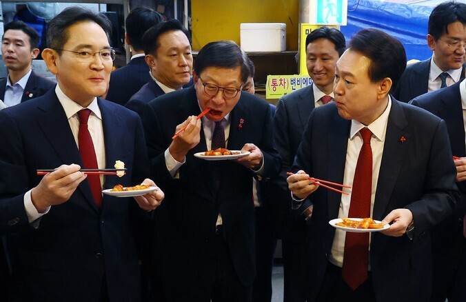 President Yoon Suk-yeol of South Korea (right) eats tteokbokki with business bigwigs, including Lee Jae-yong of Samsung Electronics, at a market in Busan on Dec. 6, 2023.
