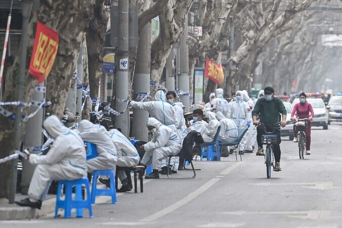 Disease control workers in protective gear sit on March 14 near an area in Shanghai where a COVID-19 case was confirmed, leading to a lockdown. (AFP/Yonhap News)
