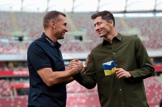 우크라이나 축구 전설 안드리 셰우첸코(왼쪽)가 폴란드 축구 국가대표팀 주장 로베르트 레반도프스키에게 우크라이나 국기 색깔 주장 완장을 전한 뒤 손을 맞잡고 있다. 레반도프스키 트위터 갈무리