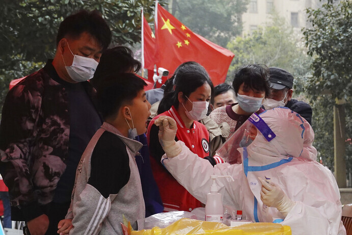 A medical worker takes a sample from a young man in Changzhou, Jiangsu Province, on March 14 to screen for COVID-19 infection. (AP/Yonhap News)