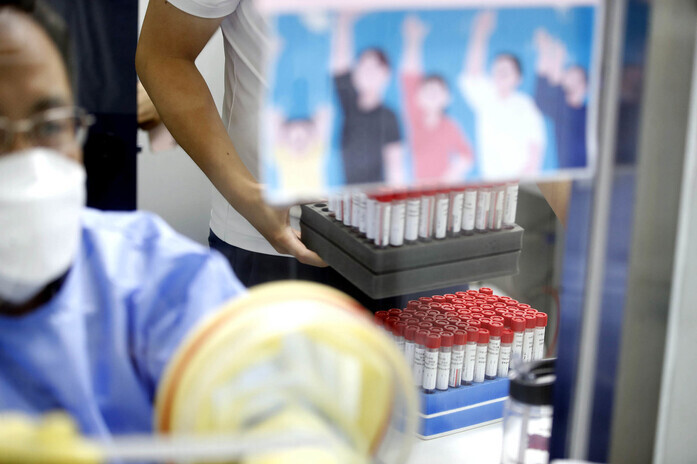 A worker at a public health center in Gwangju carries specimen samples to test for COVID-19 on Aug. 16. (Yonhap News)