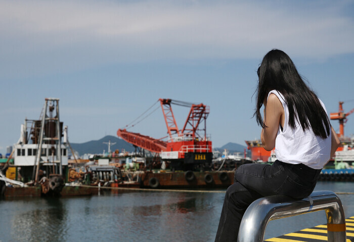 A traveler sits near a pier in Busan’s Bongnae. (Park Mee-hyang/The Hankyoreh)