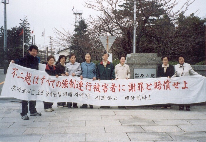 Na Hwa-ja (fourth from right) and other victims of forced labor demand compensation and an apology from Fujikoshi outside of the steel company’s headquarters in Toyama, Japan, on April 1, 2003. (courtesy of the Center for Historical Truth and Justice)