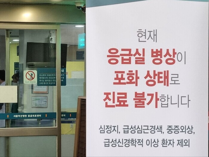 A sign outside the door to the urgent care center at the Asan Medical Center in Seoul says that treatment is not available due to emergency room beds being full as of Feb. 20, 2024. A monitor that would usually display wait times has been turned off. (Go Na-rin/The Hankyoreh)