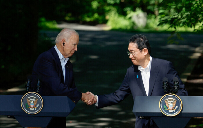US President Joe Biden (left) shakes hands with Japanese Prime Minister Fumio Kishida following the trilateral summit with Korea at Camp David in August 2023. (Reuters/Yonhap)