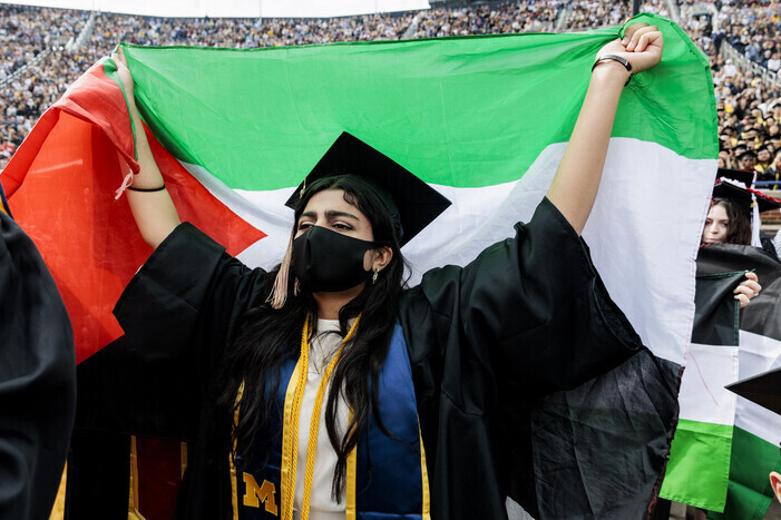 A graduate at the University of Michigan raises the Palestinian flag at the university’s graduation ceremony on May 4, 2024. (AP/Yonhap)