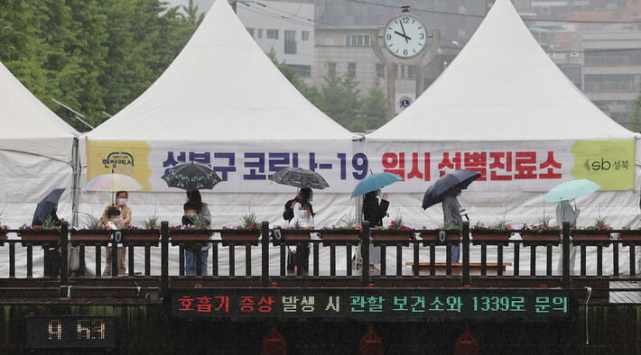 16일 오전 서울 성북구청 앞에 설치된 임시선별진료소에서 시민들이 우산을 쓰고 검사를 위해 대기해 있다. 연합뉴스