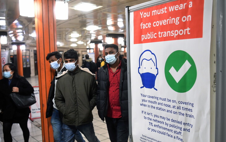 보리스 존슨 영국 총리가 코로나19 관련 방역 조처를 모두 풀겠다고 선언한 19일(현지시각) 런던 지하철 승객들이 마스크 착용 의무화를 알리는 안내판 옆을 지나가고 있다. 런던/EPA 연합뉴스