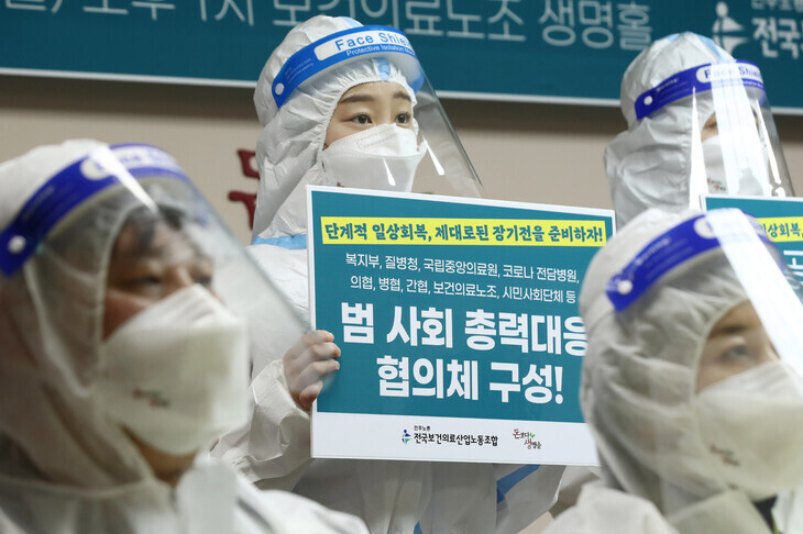 Members of the Korean Health and Medical Workers’ Union hold an emergency press conference at their headquarters in Seoul’s Yeongdeungpo District on Monday afternoon, where they shared testimonies from the front lines and called for an overhaul of the COVID-19 medical response system. (Yonhap News)