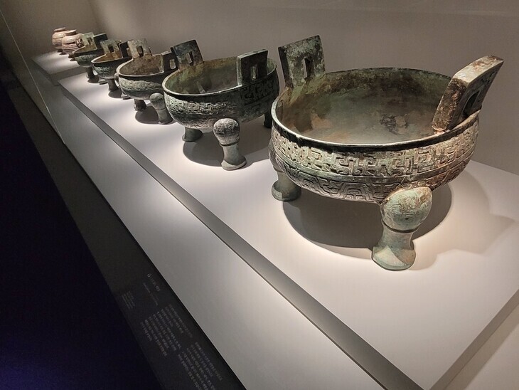 A line of tripod cauldrons, all with the same shape and pattern, but of different sizes. Lieding cauldrons were ritual vessels used in the 8th to 7th centuries BCE during the Spring and Autumn period. The number of cauldrons and the types of food contained in them differed according to status and class. (Roh Hyung-suk/The Hankyoreh)