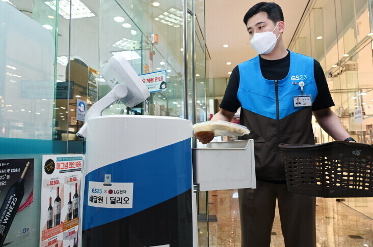 A convenience store worker at GS Tower in Gangnam District, Seoul, loads an LG CLOi ServeBot with items ordered by customers. (provided by LG Electronics)