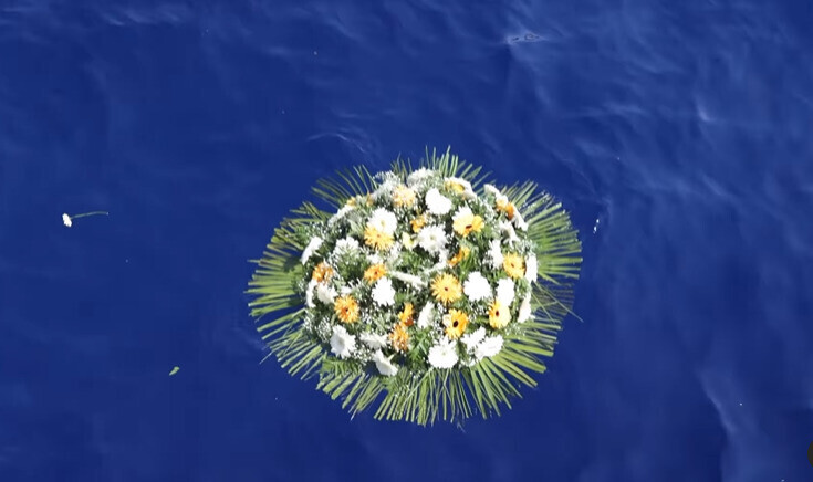 A floral wreath floats on the waters off Lampedusa on Oct. 3 to commemorate the lives of those lost there 10 years prior when a boat carrying more than 500 migrants sank. (still from Oct. 3 committee video)