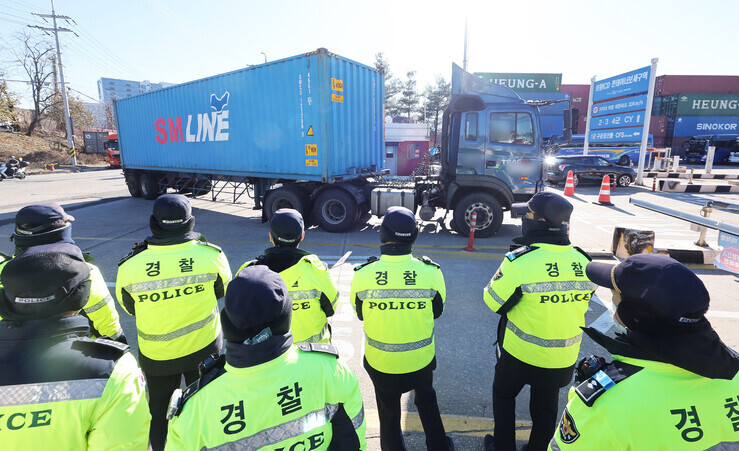Police watch as a freight truck pulls a container at an inland container depot in Uiwang, Gyeonggi Province on Dec. 5, the 12th day of the TruckSol strike. (Yonhap)