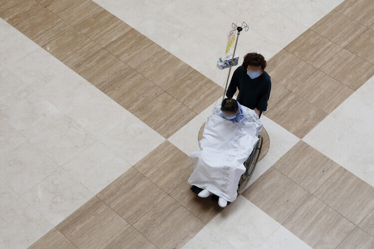 A person pushes a patient at a university-affiliated hospital in Seoul through a lobby on June 9, 2024. (Yonhap)