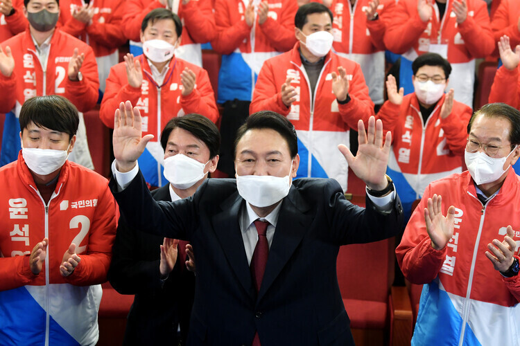 President-elect Yoon Suk-yeol waves his hands while watching vote tallies come in early on March 10. (pool photo)