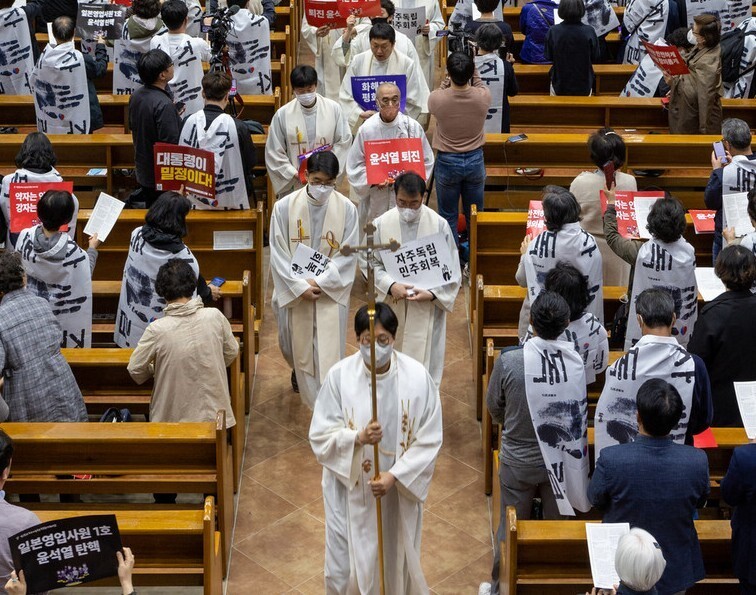 Members of the Catholic Priests' Association for Justice march out of a cathedral in Suwon on April 24 following their prayer meeting there. (Park Seung-hwa/The Hankyoreh)