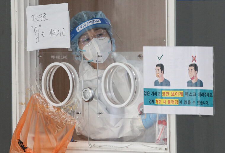 A health worker looks out the window for the next person in the line at a temporary screening center set up at Seoul Station on Monday. (Yonhap News)