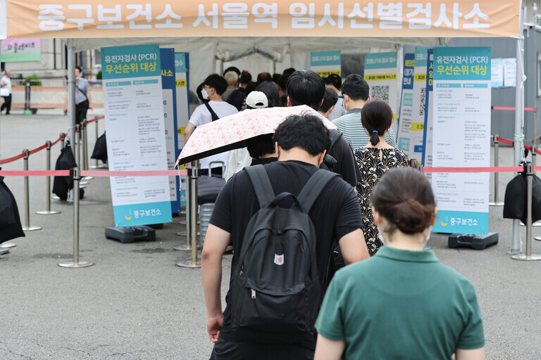 People wait in line at a COVID-19 screening station outside Seoul Station on Aug. 2. (Yonhap News)