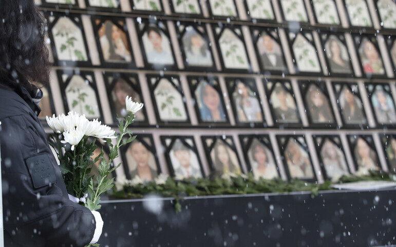 A person holds white chrysanthemums, a flower used in mourning, on Dec. 15 at the citizen-erected memorial altar for those killed in the crowd crush that took place in an alley in Itaewon on Oct. 29. (Shin So-young/The Hankyoreh)