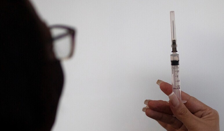 A health worker inspects a syringe with a dose of COVID-19 vaccine. (AP/Yonhap News)