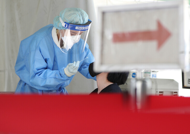 A worker collects a sample for a PCR test at a COVID-19 screening station in Daegu on May 11. (Yonhap)