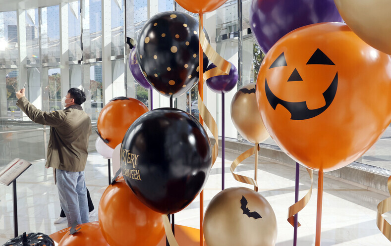 Shoppers pause to take a photo in front of Halloween decorations at the Lotte World Tower in Jamsil, Songpa District, on Friday afternoon. (Yonhap News)
