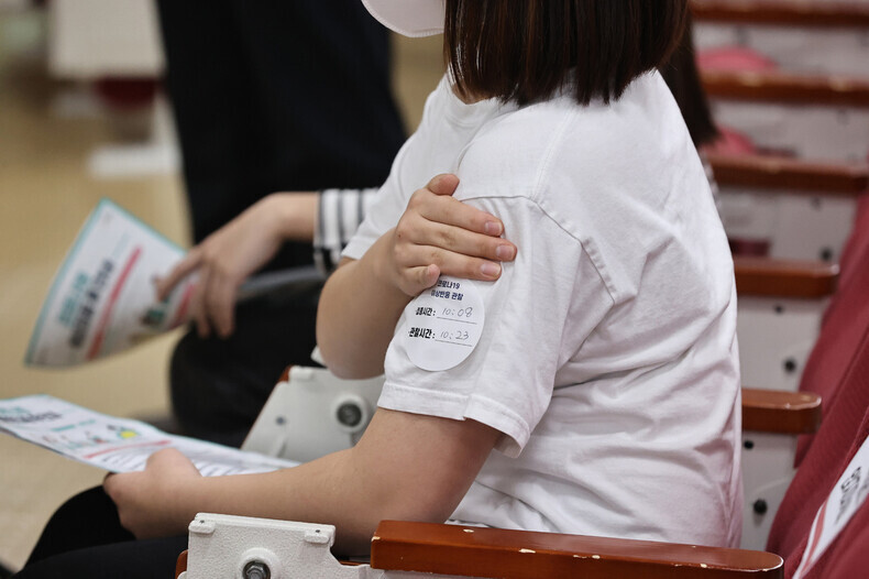A person sits to be monitored after receiving a COVID-19 vaccine at a school in Gyeonggi Province on Tuesday morning. (pool photo)