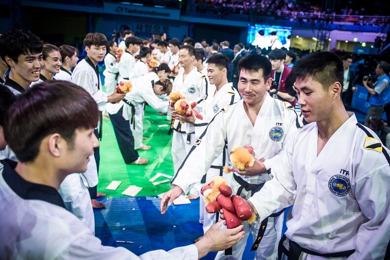 South and North Korean members of a taekwondo demonstration team exchange gifts following a performance at the opening ceremony of the 2017 World Taekwondo Championships in Muju