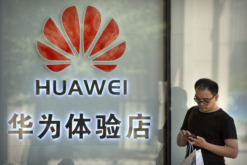 A man uses a smartphone in front of a Huawei store in Beijing. (AP/Yonhap News)