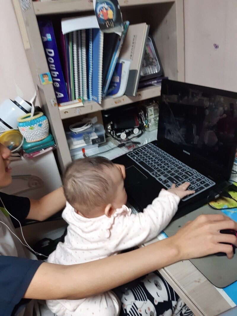 Hyeon-seo holds his youngest sister as he uses the computer. (courtesy of Hyeon-seo’s family)