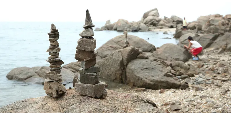 Visitors will find rocks stacked into little cairns all across the shore at Baemikkumi Sculpture Park. (Park Mee-hyang/Hankyoreh)