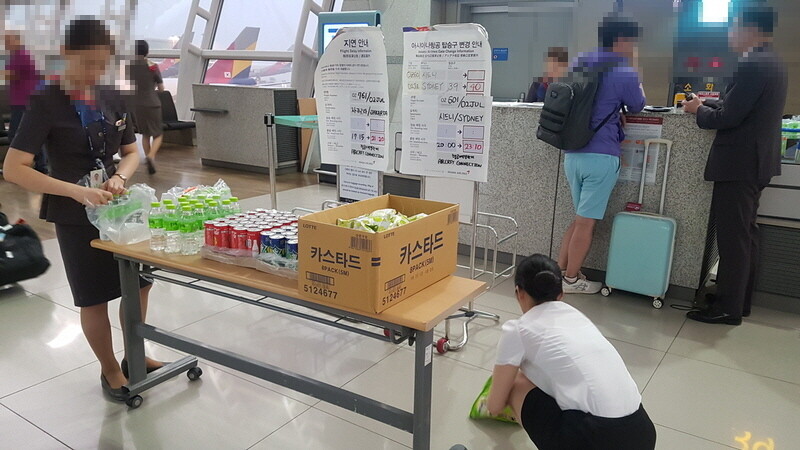 Asiana Airlines employees prepare snacks for passengers in front of a departure gate at Incheon International Airport on July 2 after two continuous days of supply shortages for in-flight meals resulted in several no-meal flights and takeoff delays. (Kim Mi-young