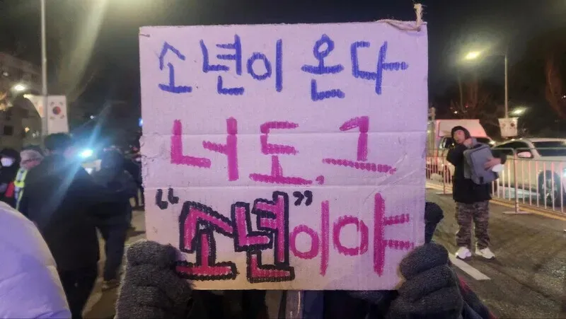 A woman who introduced herself as “just another unemployed 30-something” holds up a sign referencing the Han Kang novel “Human Acts” that she crafted while watching martial law troops storm the National Assembly in December 2024. (Yoon Woon-sik/Hankyoreh)