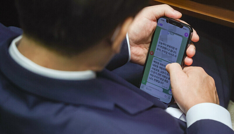 Lee Jae-myung, lawmaker and leader of the Democratic Party, checks a text message on Sept. 1 from chief advisor Kim Hyeon-ji informing Lee that a summons was delivered for him in regard to development scandals in Seongnam, where he formerly served as mayor. Kim’s text message ends with the line, “This is war.” (pool photo)