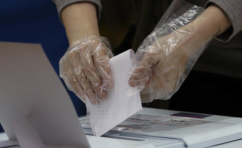 A South Korean voter wearing disposable gloves casts a ballot at a polling station in Seoul’s Jongno District on Apr. 10. (Lee Jong-keun, staff photographer)