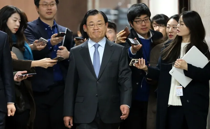 Former Blue House Chief of Staff Lee Byung-kee walks through a crowd of reporters on his way to the Democratic Party leader’s office at the National Assembly on Feb. 19