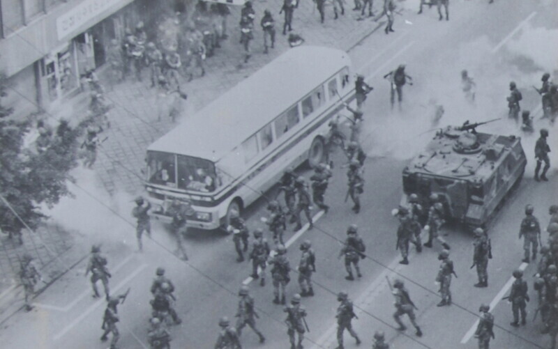 Martial law forces mobilize a caterpillar-track armored vehicle as they round up Gwangju citizens on a bus during the uprising and massacre in the city in May 1980. (from the Defense Security Demand photo archive)