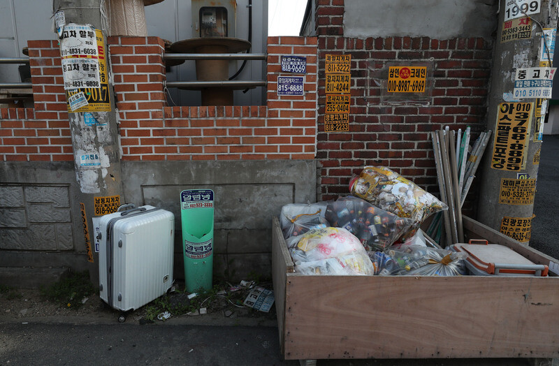 A travel suitcase is discarded near a factory dumpster in Incheon’s Namdong District