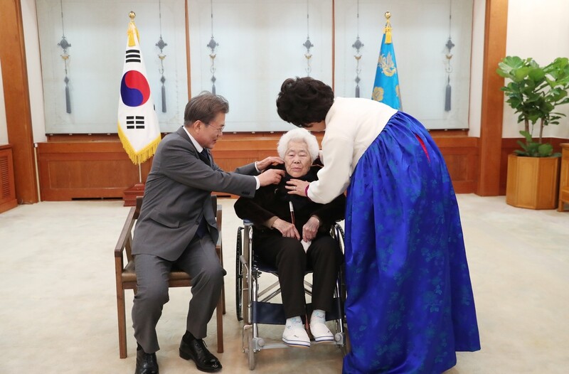 President Moon Jae-in adjusts the sweater of comfort woman survivor Lee Ok-seon prior to taking a commemorative photo at the Blue House on Jan. 4. (provided by Blue House)