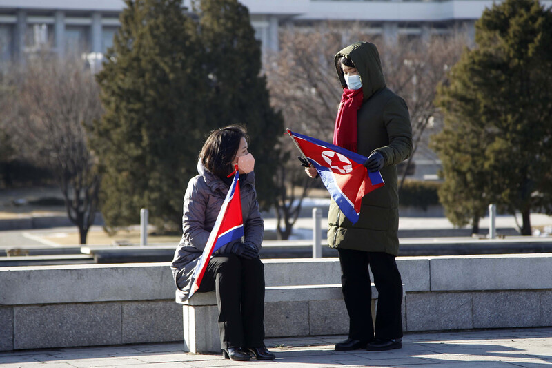 북한 평양에 위치한 인민대학습당 앞에서 24일 마스크를 착용한 두 여성이 인공기를 든 채 대화하고 있다. 연합뉴스
