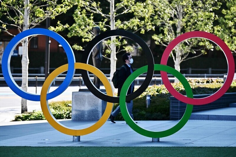 A man walks behind the Olympic Rings installed in front of the Japan National Stadium in Tokyo. (AFP/Yonhap News)