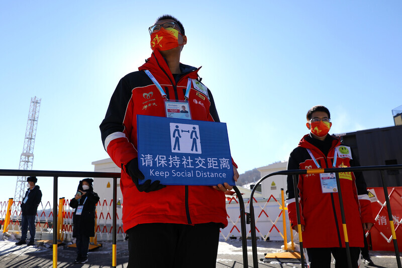 Event staff at the FIS Ski Cross World Cup, held at Zhangjiakou’s Genting Resort Secret Garden in China’s Hebei Province, hold up signs about social distancing on Saturday. (Reuters/Yonhap News)
