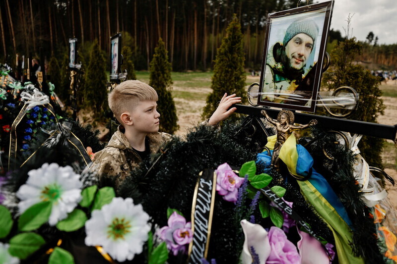 A boy stands at the grave of his father, killed by Russian forces, outside of Kyiv, Ukraine, on May 1. (Reuters/Yonhap News)